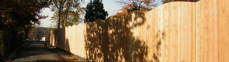 Unpainted wooden fence. Curving at the top